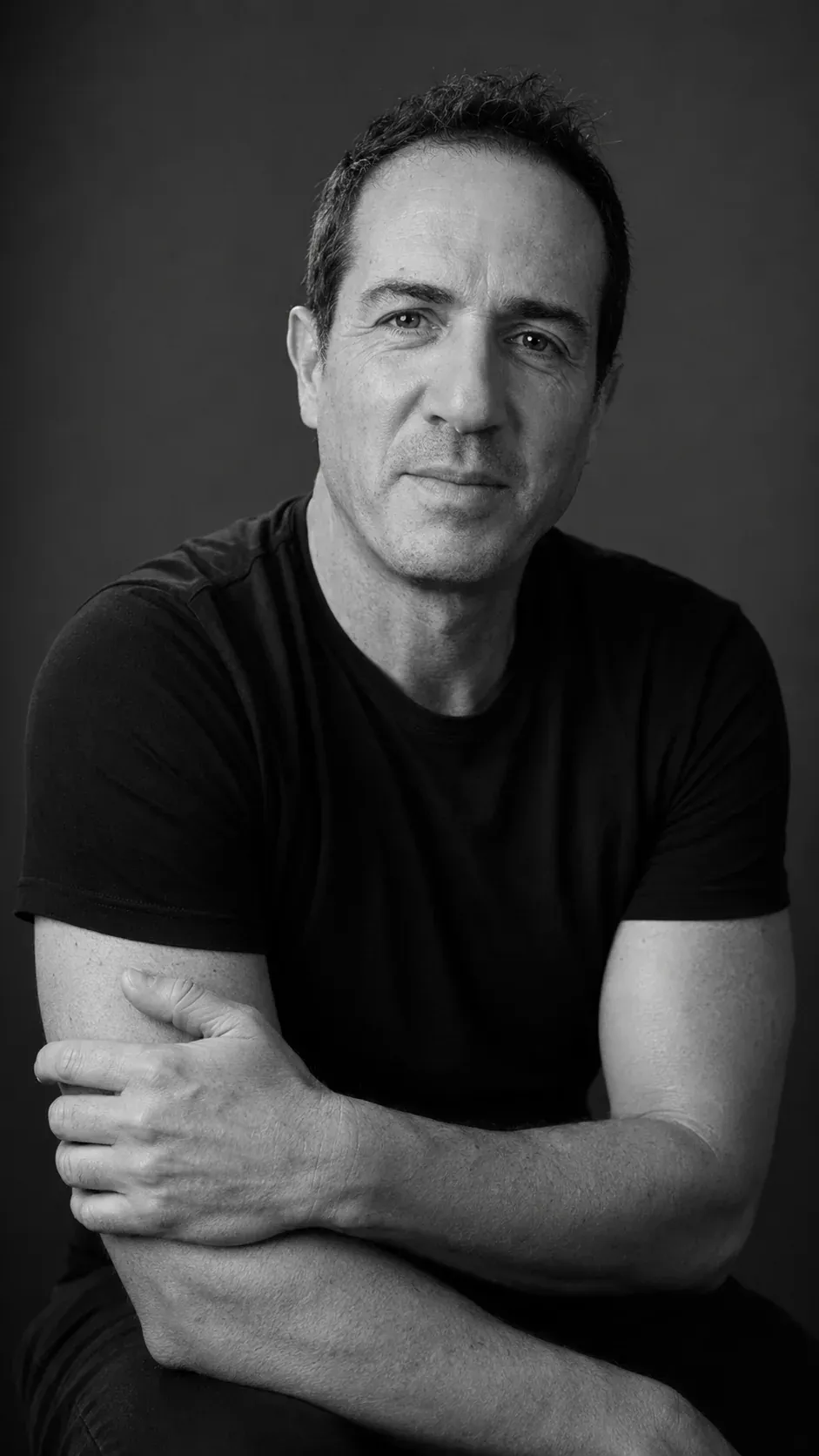 Retrato en blanco y negro de Joctan González, sentado y con los brazos cruzados